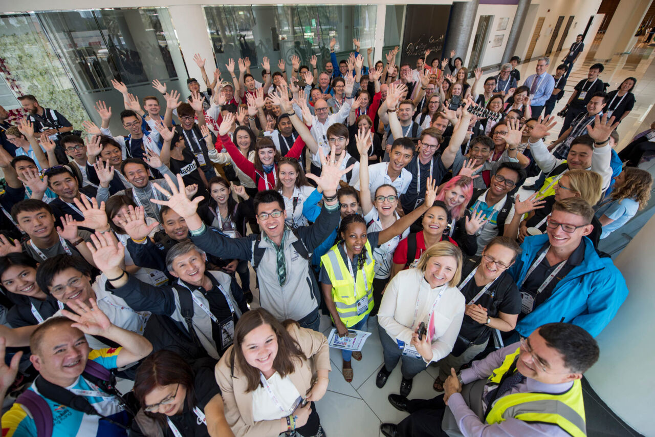 A panoramic group photo of attendees at WorldSkills Abu Dhabi 2017 waving and smiling at the camera.